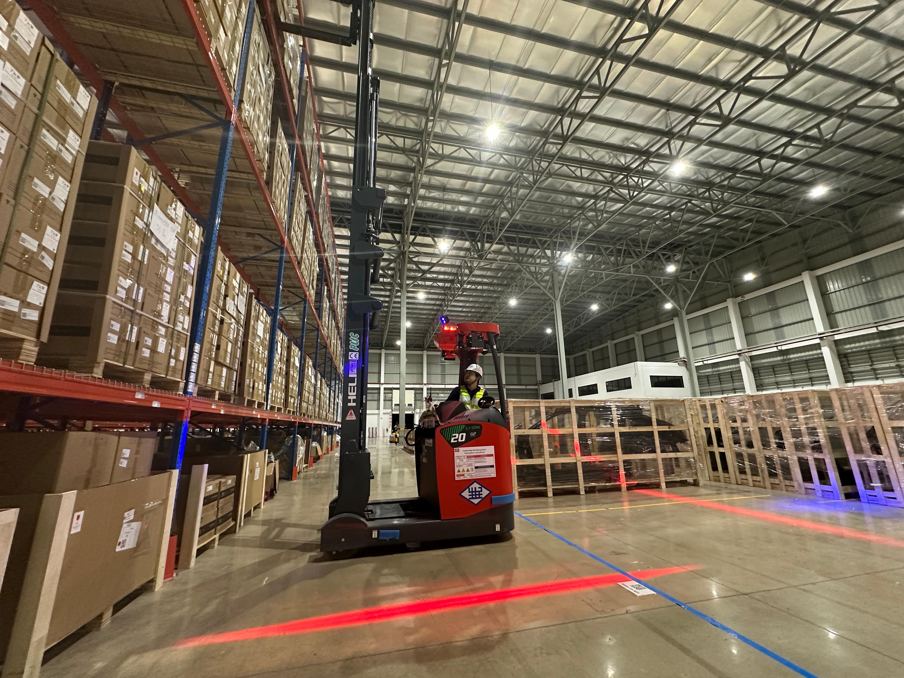 Forklift handling palletized inventory in a warehouse storage aisle